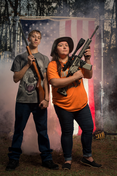 Portrait 1 from the An American Christmas series, person posing with a rifle in front of an American flag backdrop