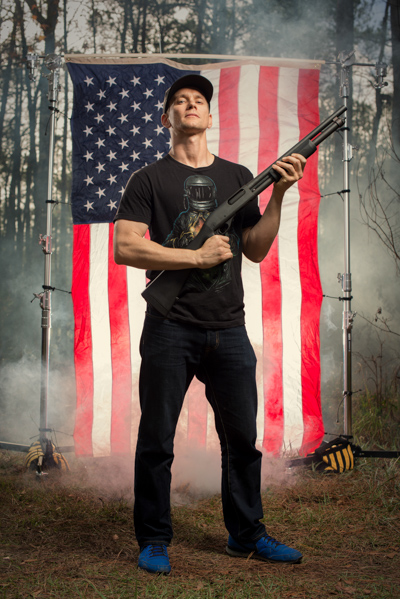 Portrait 5 from the An American Christmas series, person posing with an AR-style rifle in front of an American flag backdrop