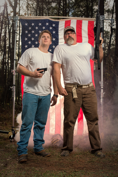 Portrait 16 from the An American Christmas series, person posing with a hunting rifle in front of an American flag backdrop