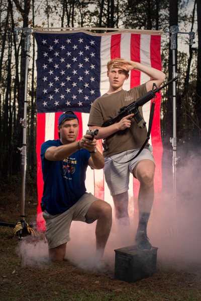 Portrait 19 from the An American Christmas series, person posing with a rifle in front of an American flag backdrop