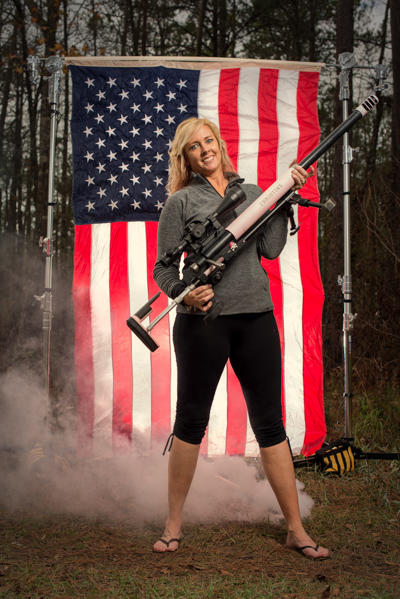 Portrait 29 from the An American Christmas series, person posing with an AR-style rifle in front of an American flag backdrop