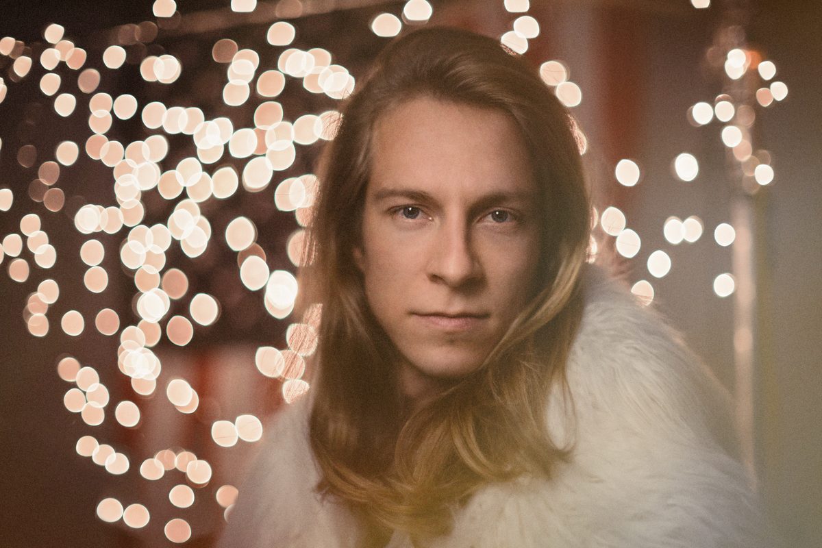 Man with long blond hair, portrait lit with warm bokeh lights