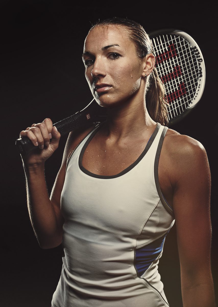 Close-up of a woman holding a tennis racket against her shoulder, serious expression