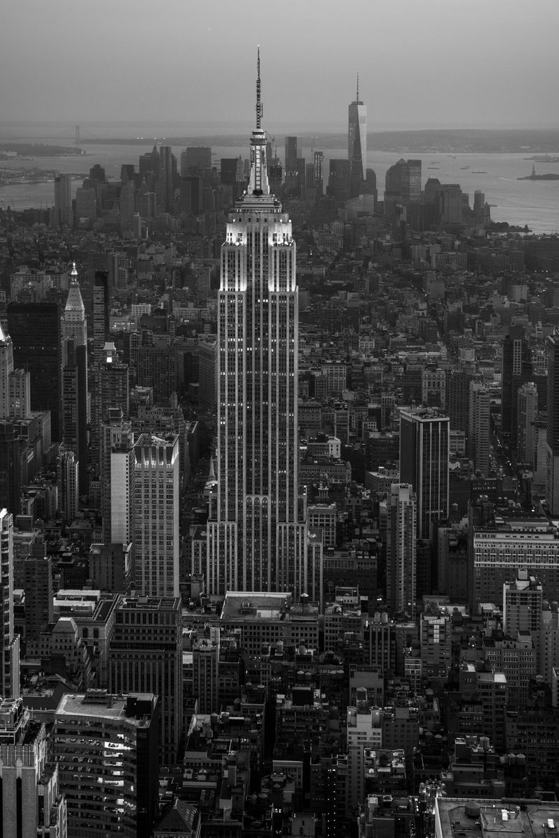 Black-and-white aerial view of the Empire State Building rising above the Manhattan skyline