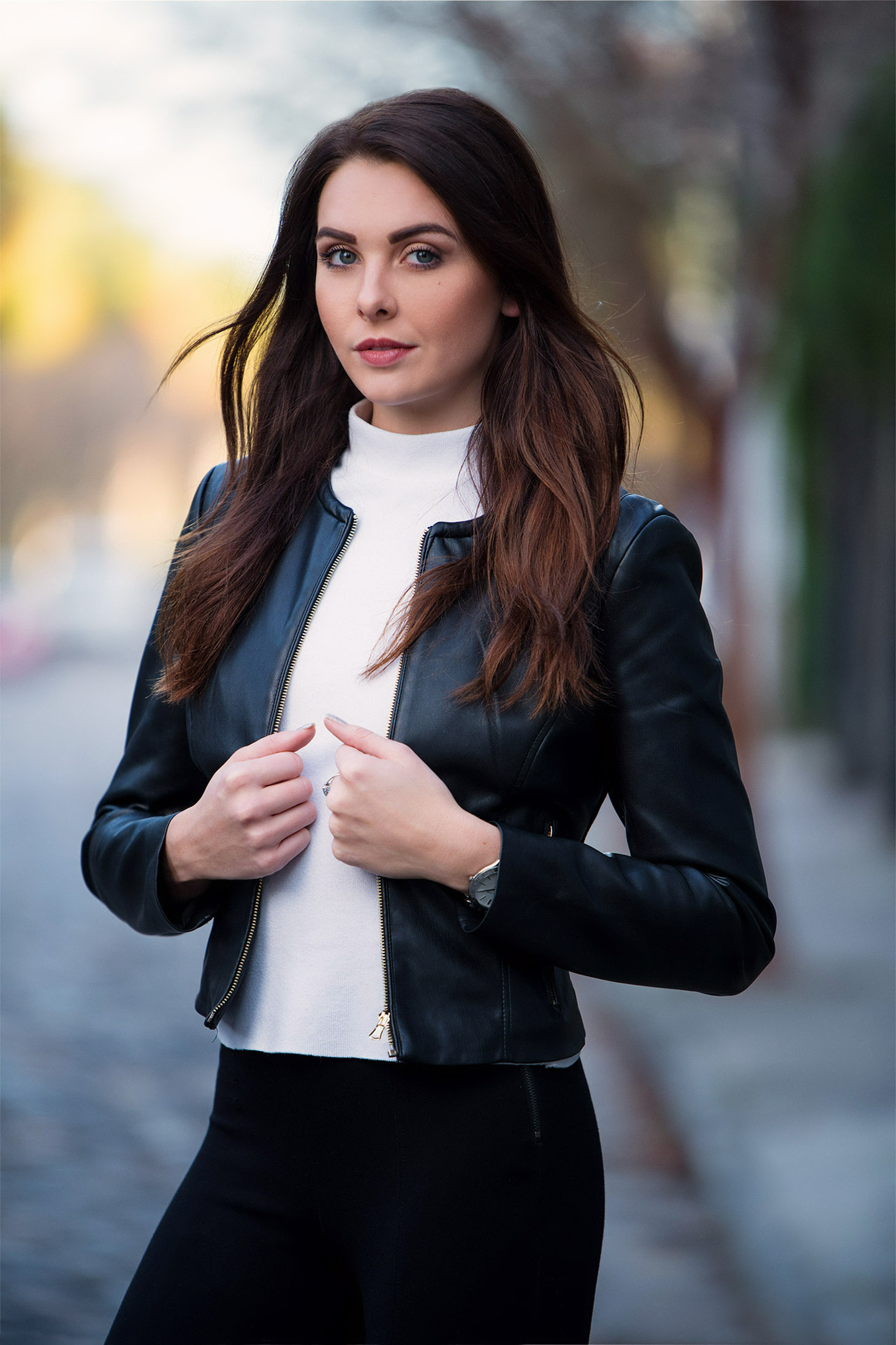 Woman in a black leather jacket walking on a city sidewalk