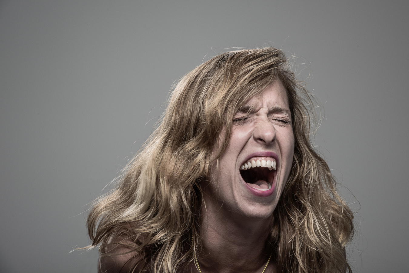 Studio headshot portrait 1 from the Stun Gun Photoshoot series, person wincing with eyes shut as they are hit with a stun gun
