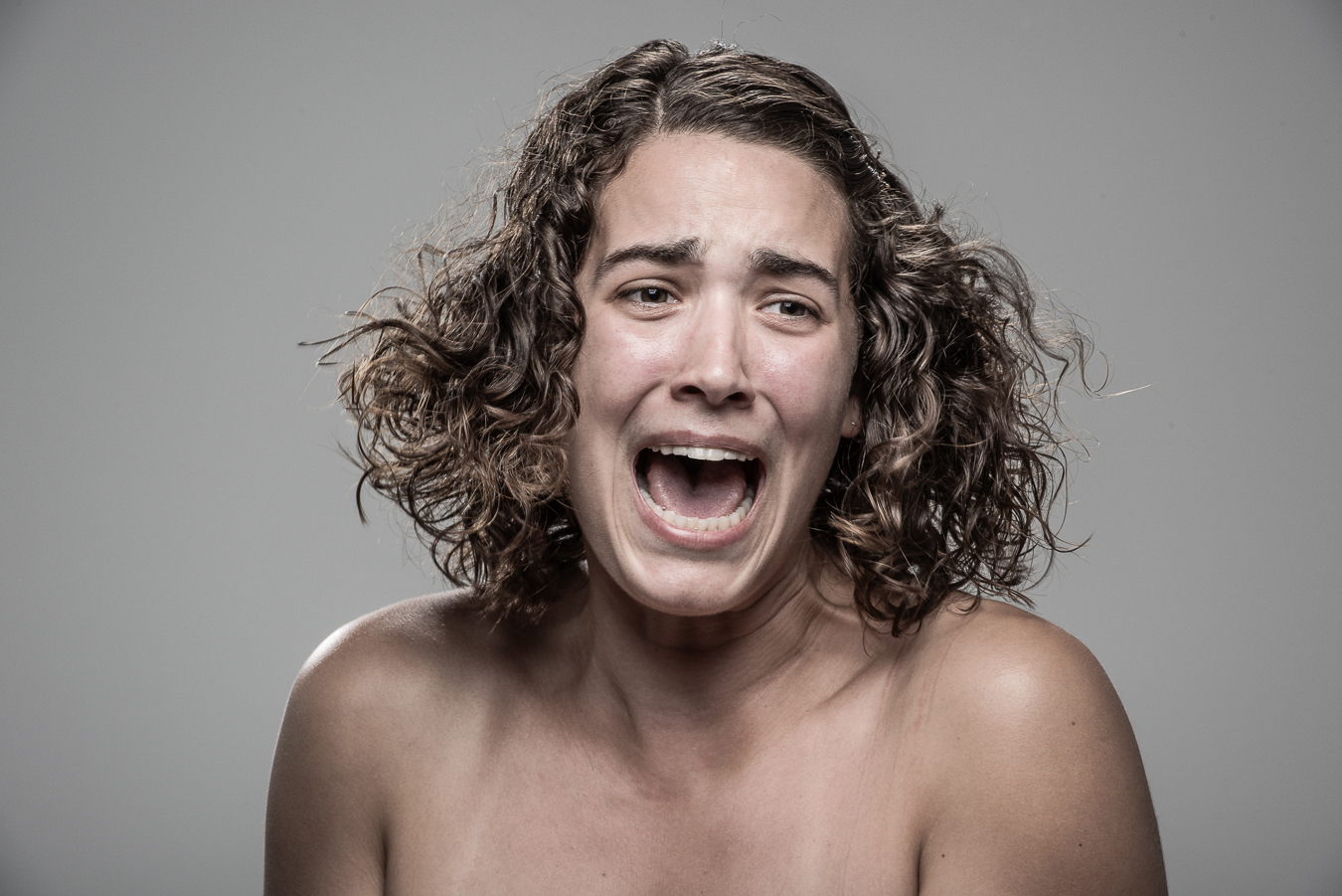 Studio headshot portrait 6 from the Stun Gun Photoshoot series, person grimacing with clenched teeth as they are hit with a stun gun