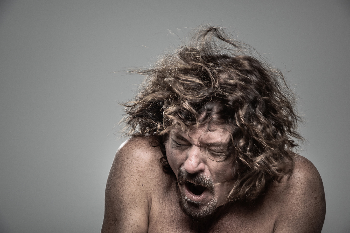 Studio headshot portrait 7 from the Stun Gun Photoshoot series, person wincing with eyes shut as they are hit with a stun gun