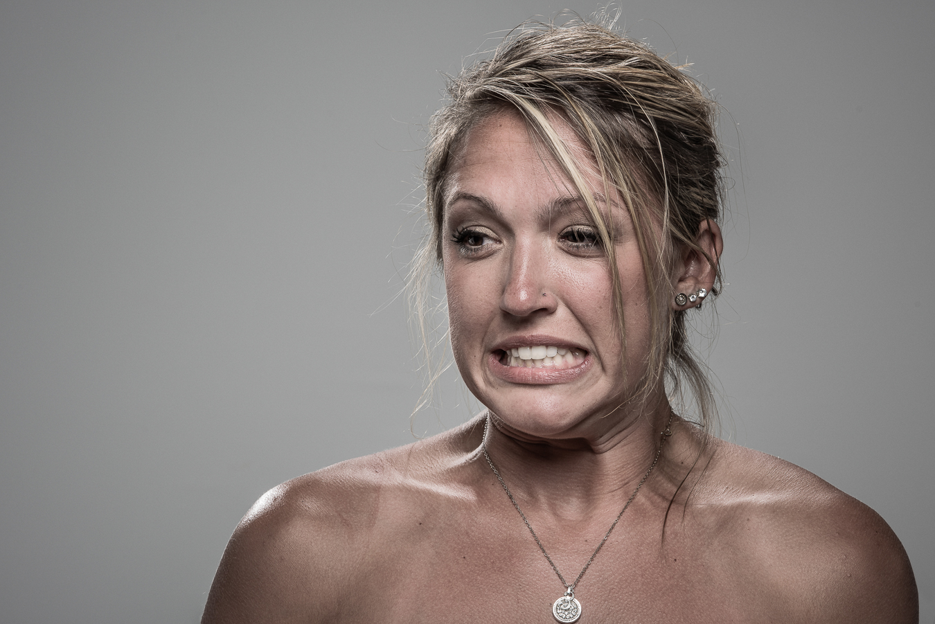 Studio headshot portrait 25 from the Stun Gun Photoshoot series, person wincing with eyes shut as they are hit with a stun gun