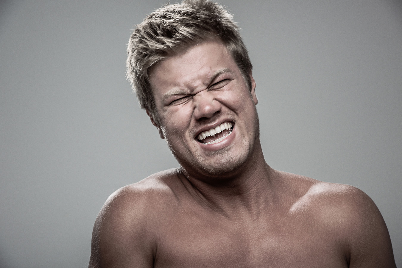Studio headshot portrait 36 from the Stun Gun Photoshoot series, person grimacing with clenched teeth as they are hit with a stun gun