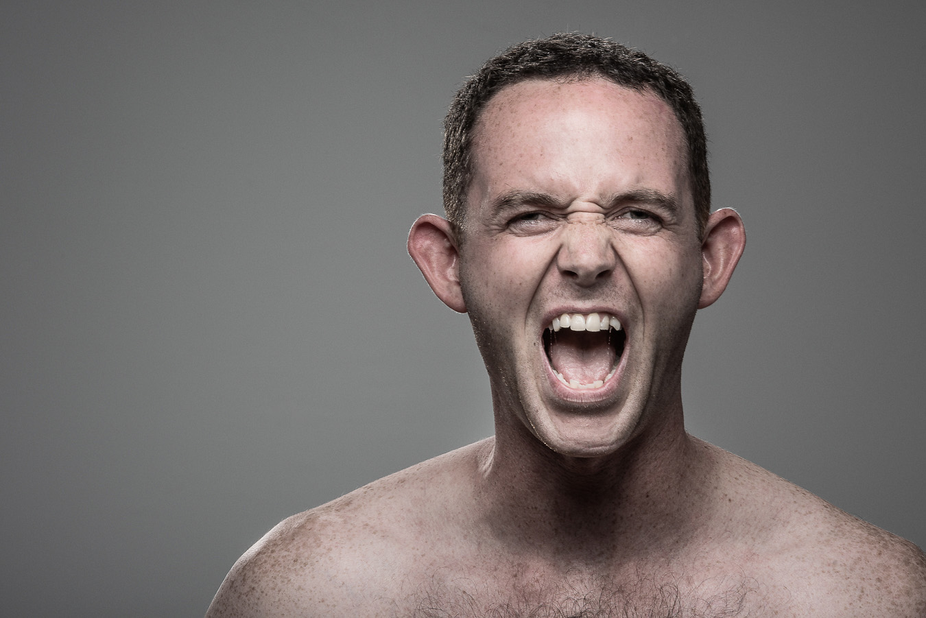 Studio headshot portrait 37 from the Stun Gun Photoshoot series, person wincing with eyes shut as they are hit with a stun gun
