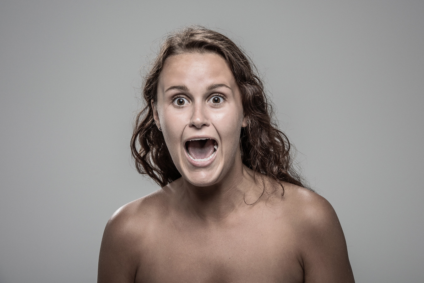 Studio headshot portrait 45 from the Stun Gun Photoshoot series, person flinching and grimacing as they are hit with a stun gun