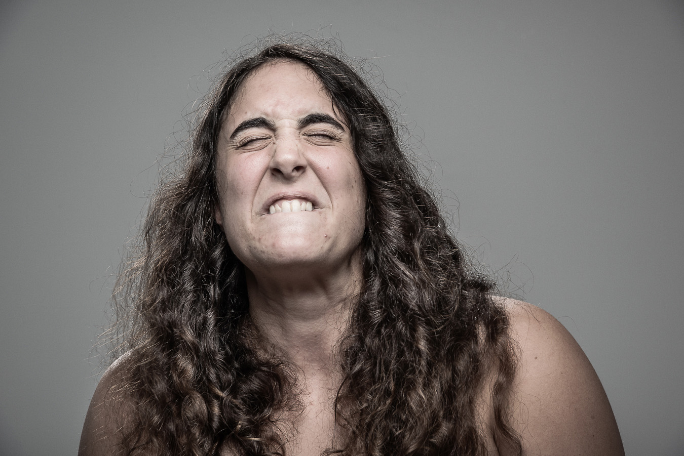 Studio headshot portrait 48 from the Stun Gun Photoshoot series, person grimacing with clenched teeth as they are hit with a stun gun