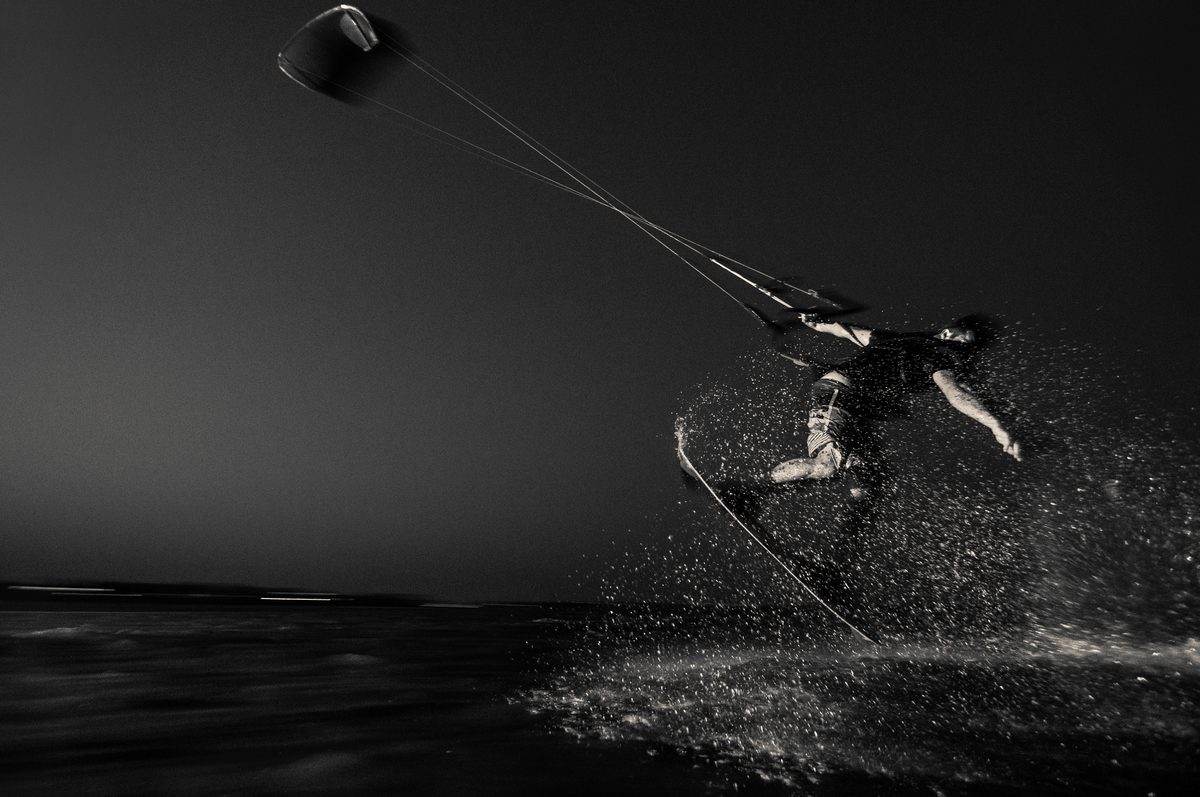 Black and white photo of a wakeboarder jumping with a large splash