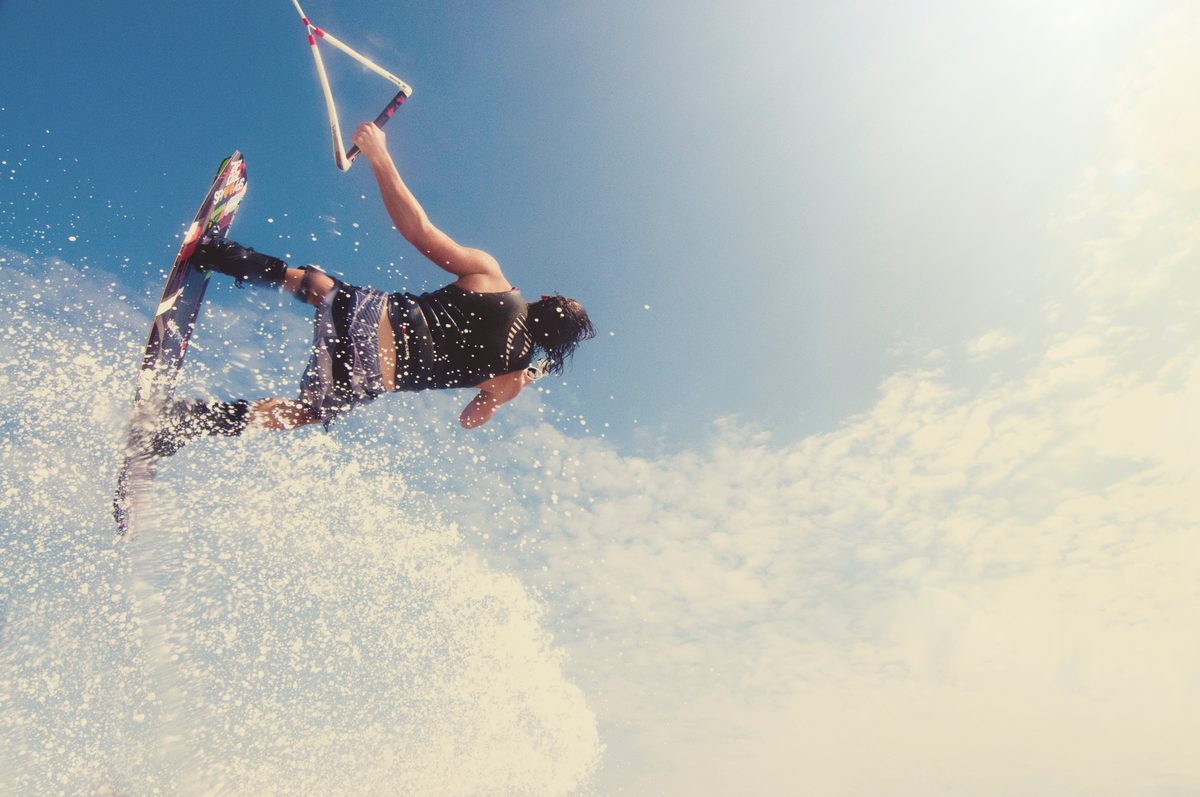 Wakeboarder flipping through a large spray of whitewater